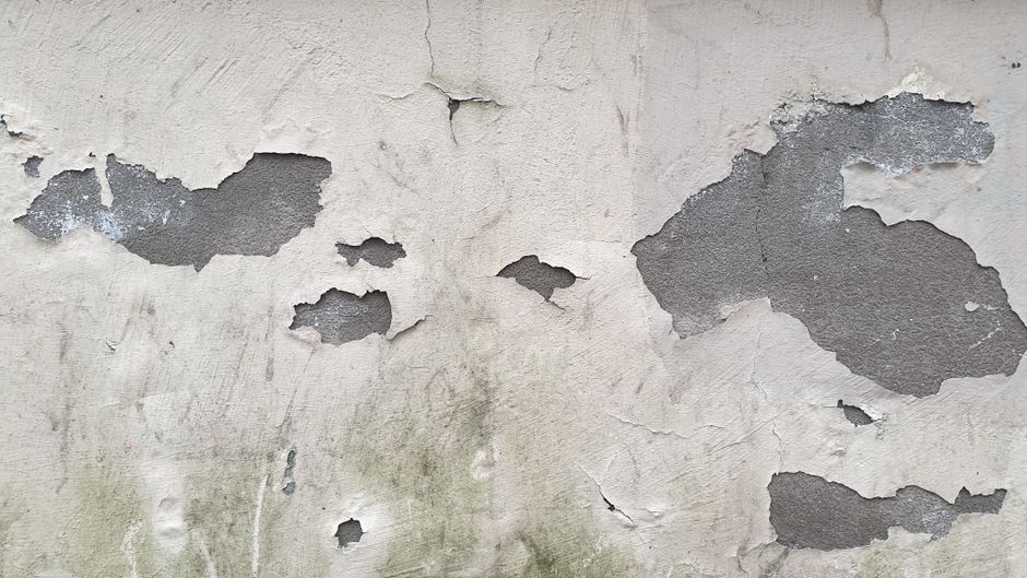 Close-up of a wall surface with peeling paint and a crack