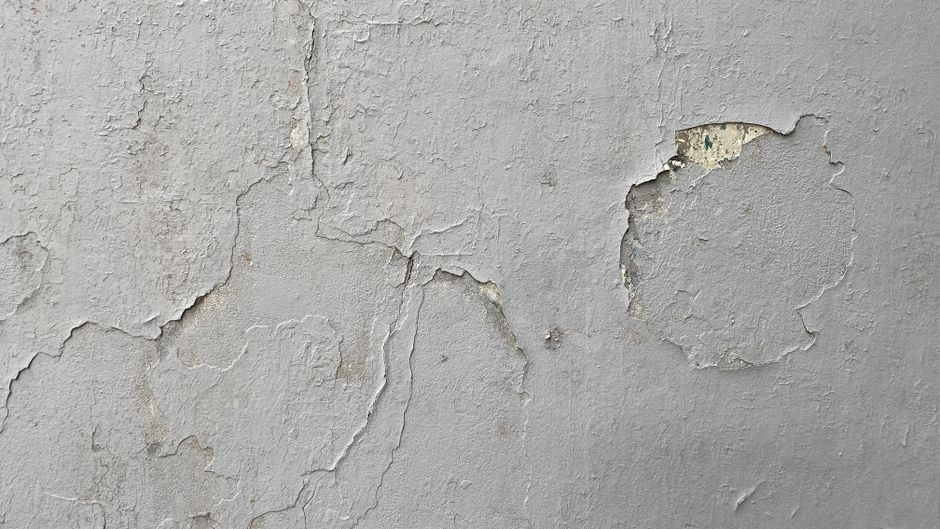 Close-up of a wall surface with peeling paint and cracks